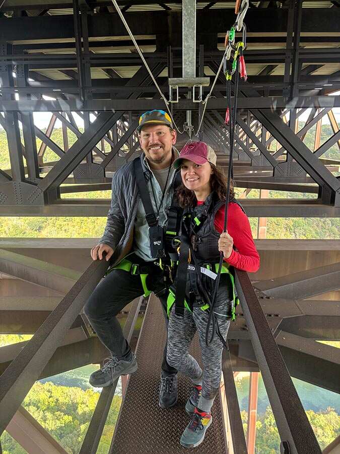 Couple in harnesses on the catwalk high above the river