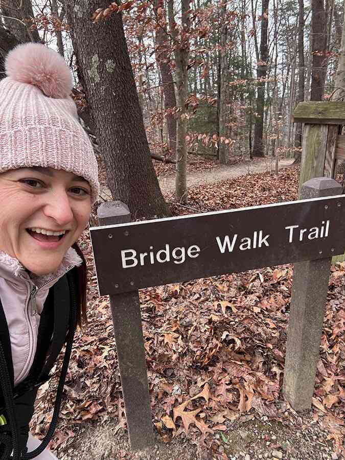Smiling walker at the Bridge Walk Trail sign in winter